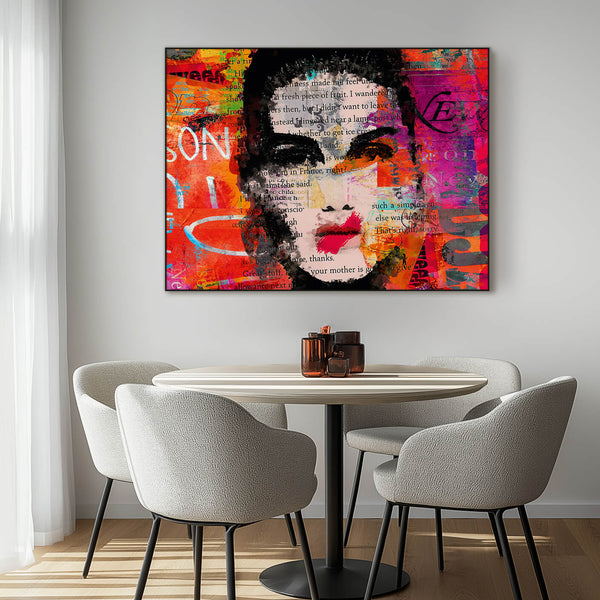 Abstraktes Gemälde einer Frau mit schwarzem Haar vor einem bunten Hintergrund in Orange-, Rot- und Lilatönen.  Im Hintergrund sind Textfragmente und eine pinkfarbene Rose zu sehen. Das Bild hängt an einer weißen Wand über einem Esstisch mit weißen Stühlen in einem modernen Esszimmer.