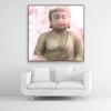 Tysta Akustikbild Asien Buddha mit Buddhastatue und rosa Kirschblüten. Schwarzer Bilderrahmen im Quadrat über weißem Sofa.