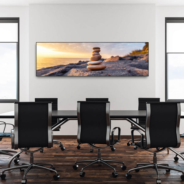 Moderner Konferenzraum mit Tisch und schwarzen Stühlen und Schallschutzbild mit Steinhaufen bei Sonnenaufgang mit schwarzem Rahmen im Querformat..