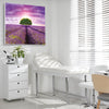 Heller Behandlungsraum eines Arztes mit Schallschutzbild Dreamy mit Lavendelfeld, lila farbenen Himmel und Baum. Weißer Rahmen im Quadrat über weißer Behandlungsliege.