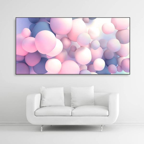 Schallschutzbild mit rosa-blau pastellfarbenden Ballons in unterschiedlicher Größe frei schwebend. Schwarzer Bilderrahmen im Querformat 2 zu 1 über weißem Sofa.