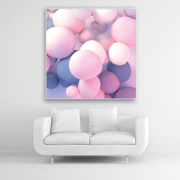 Schallschutzbild mit rosa-blau pastellfarbenden Ballons in unterschiedlicher Größe frei schwebend. Weißer Bilderrahmen im Quadrat über weißem Sofa.