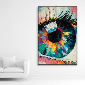 Schallschutzbild mit dick aufgetragener Farbe gemaltes, abstraktes Auge in bunten Farbtönen. Schwarzer Rahmen im Hochformat neben weißem Sofa.