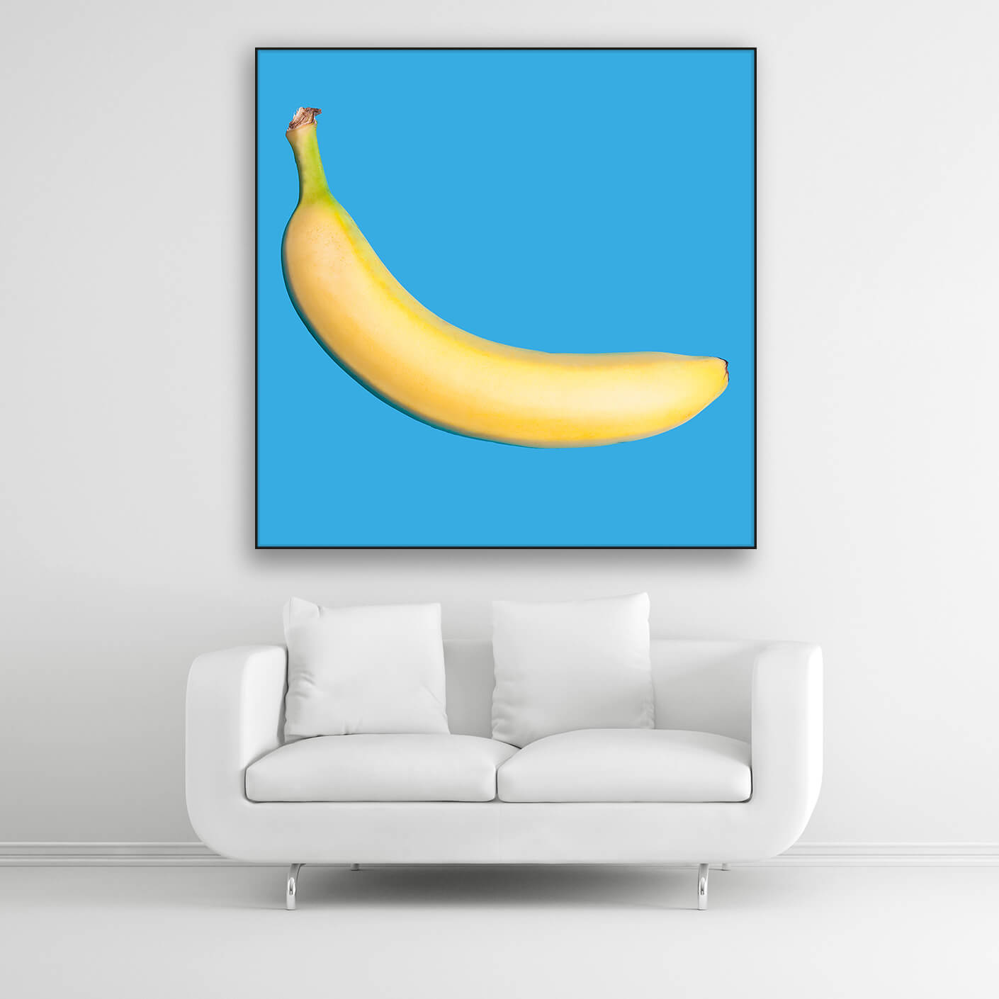 Tysta Akustikbild mit Fotografie einer gelben Banane auf hellblauen Hintergrund. Schwarzer Rahmen im Quadrat über weißem Sofa.