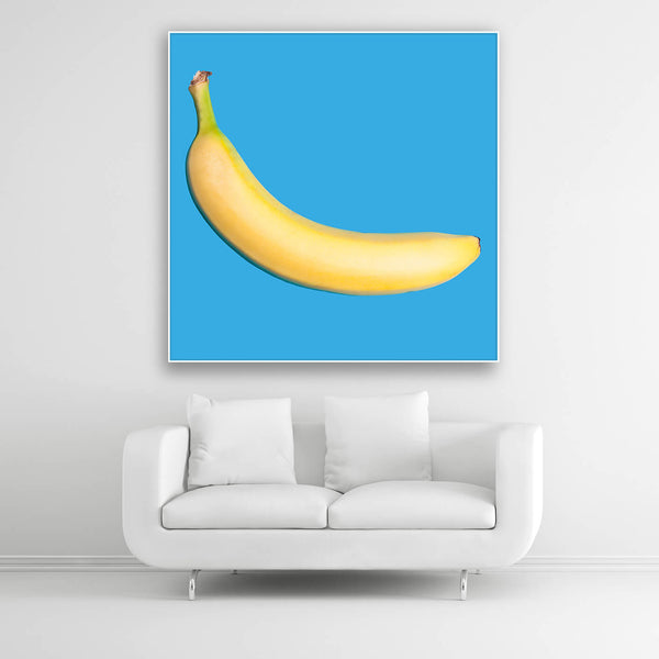 Tysta Akustikbild mit Fotografie einer gelben Banane auf hellblauen Hintergrund. Weißer Rahmen im Quadrat über weißem Sofa.