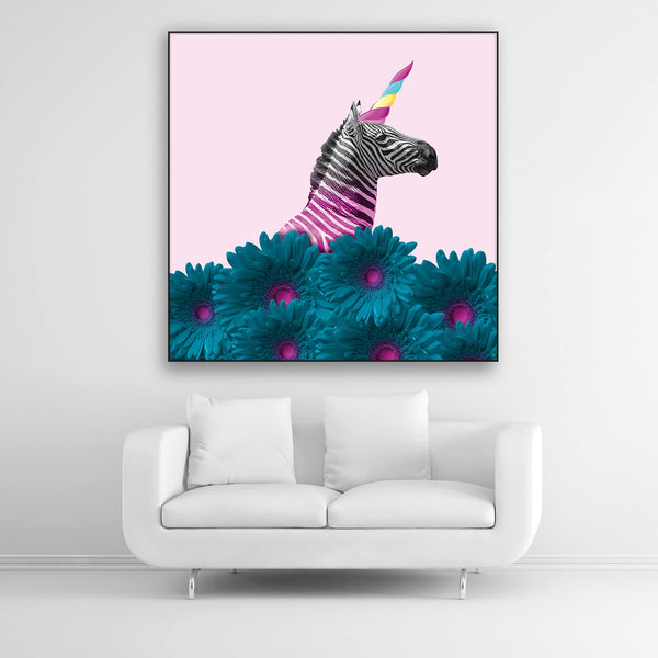 Schallschutzbild mit buntem Zebra, farbigem Horn und blau-pink eingefärbten Blumen. Schwarzer Rahmen im Quadrat über weißem Sofa.