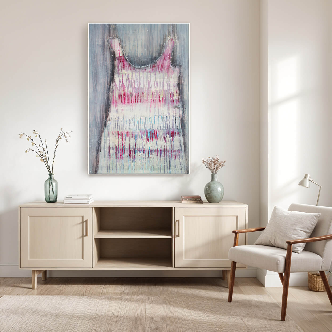 Ein abstraktes Gemälde eines Kleides hängt an einer weißen Wand über einem cremefarbenen Sideboard. Das Kleid ist in sanften Rosa- und Violetttönen gehalten, mit Farbtupfern und fließenden Linien, die eine zarte und feminine Atmosphäre schaffen. Auf dem Sideboard stehen zwei Vasen mit Zweigen und eine kleine Schale. Rechts neben dem Sideboard steht ein bequemer Sessel mit einem Kissen.