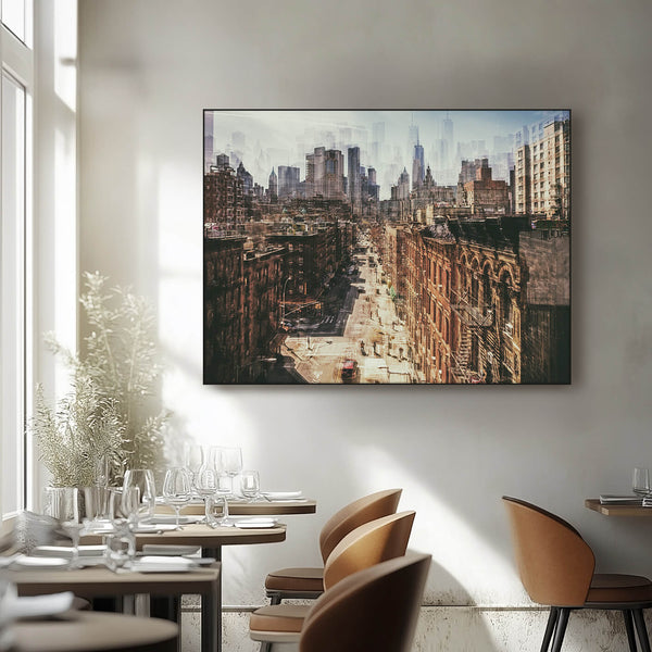 Ein gerahmtes Vintage-Foto einer belebten Stadtstraße hängt an der Wand eines hellen, modernen Restaurants. Das Foto zeigt eine Straßenschlucht mit hohen Gebäuden auf beiden Seiten und Menschen, die die Straße entlanggehen. Im Hintergrund ist eine Skyline mit Wolkenkratzern zu sehen.