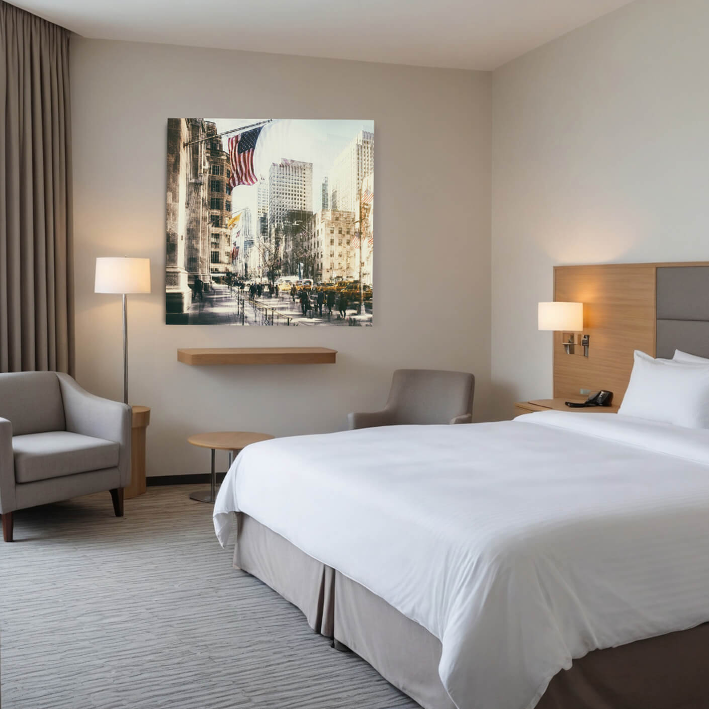 Ein modernes Hotelzimmer mit einem großen Bett, zwei Nachttischen mit Lampen, einem Sessel und einem kleinen Tisch. An der Wand hinter dem Bett hängt ein großes Foto einer belebten Straße in New York City mit der amerikanischen Flagge.