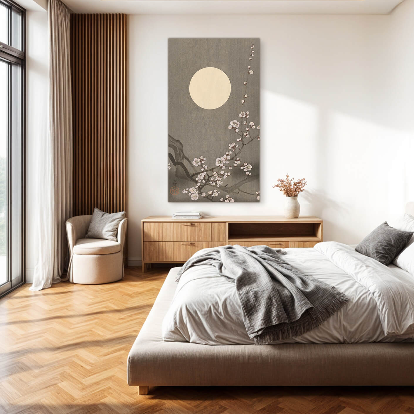 Ein traditionelles japanisches Gemälde mit einem Vollmond und blühenden Kirschblüten an einem Ast hängt über einem Bett in einem minimalistischen Schlafzimmer.