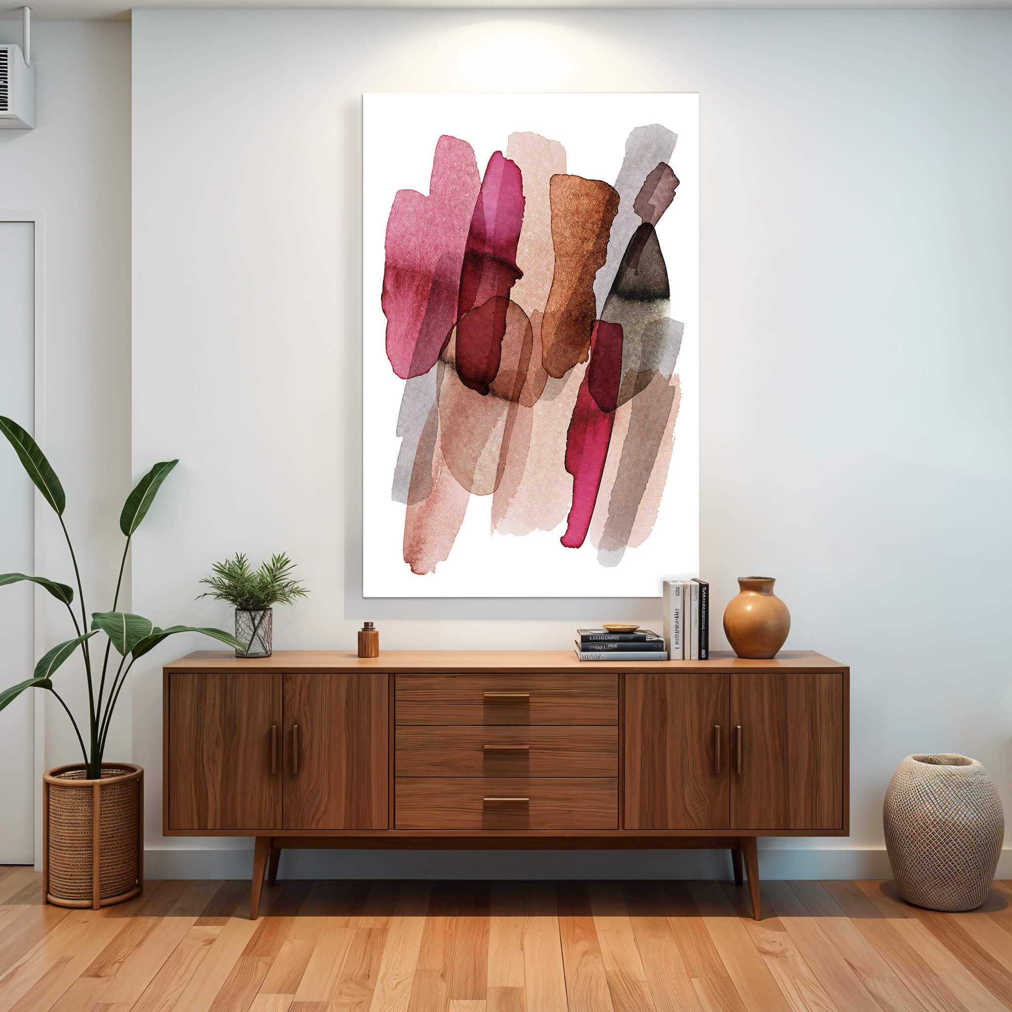 Abstraktes Gemälde mit weichen Pinselstrichen in verschiedenen Rosa-, Rot- und Brauntönen auf weißem Hintergrund. Das Bild hängt über einer modernen Kommode aus Holz im Wohnzimmer. Auf der Kommode stehen zwei Vasen und Bücher. Neben der Kommode steht eine große Pflanze in einem Topf. 