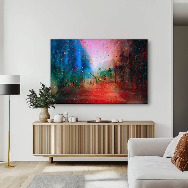 Lebendiges abstraktes Gemälde mit einem roten Pfad, der durch einen blauen und grünen Wald führt. Das Bild zeigt ein großes, horizontales Kunstwerk, das über einem hölzernen Sideboard an einer weißen Wand hängt. Das Gemälde zeigt einen verschwommenen, traumhaften Wald in Blau- und Grüntönen auf der linken Seite und rötlichen Tönen auf der rechten Seite. Ein leuchtend roter Pfad zieht sich durch die Mitte des Bildes und erzeugt Tiefe.