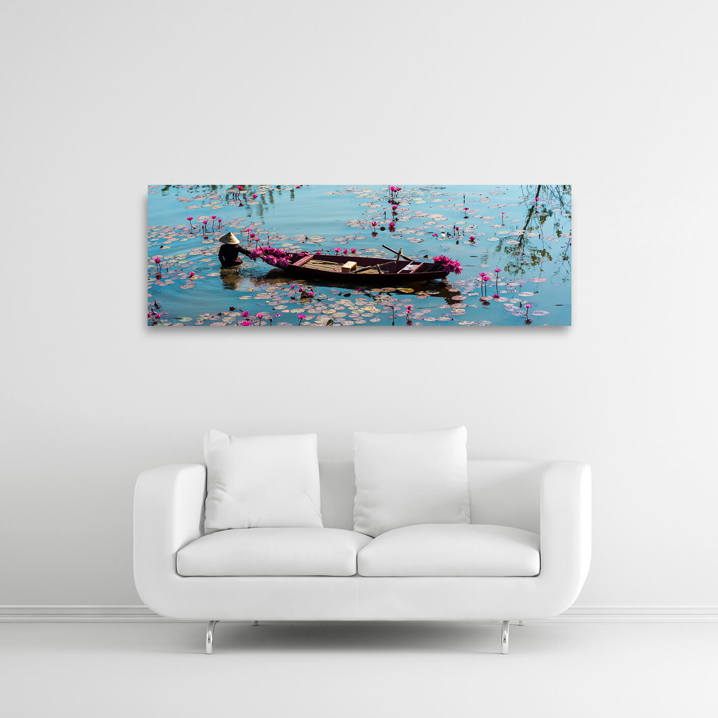 Ein großes Landschaftsbild zeigt einen ruhigen See mit zahlreichen rosa Seerosenblüten, die auf der Wasseroberfläche treiben. Ein kleines Holzboot mit einer Person an Bord gleitet langsam durch das Wasser. Bildformat 120x40cm.