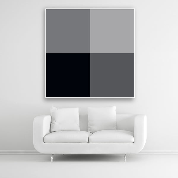 Tysta Akustikbild Colorline Black mit vier Vollfarben Schwarz und Grau. Weißer Bilderrahmen im Quadrat über weißem Sofa.