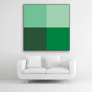 Tysta Akustikbild Colorline Green mit vier Vollfarben aus Grüntönen. Schwarzer Bilderrahmen im Quadrat über weißem Sofa.