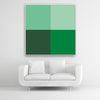 Tysta Akustikbild Colorline Green mit vier Vollfarben aus Grüntönen. Weißer Bilderrahmen im Quadrat über weißem Sofa.