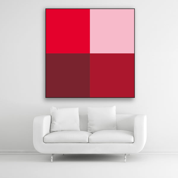 Tysta Akustikbild Colorline Red mit vier Vollfarben aus Rottönen. Schwarzer Bilderrahmen im Quadrat über weißem Sofa.