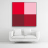 Tysta Akustikbild Colorline Red mit vier Vollfarben aus Rottönen. Schwarzer Bilderrahmen im Quadrat über weißem Sofa.