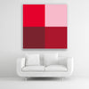 Tysta Akustikbild Colorline Red mit vier Vollfarben aus Rottönen. Weißer Bilderrahmen im Quadrat über weißem Sofa.