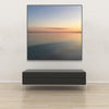 Akustikbild Silent Ocean 2 von Tan Kulali mit abstraktem Meerblick bei Sonnenuntergang. Quadratisch mit schwarzem Rahmen über Sitzbank.