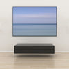 Akustikbild Silent Ocean 3 von Tan Kulali mit abstrakten Horizont in Blautönen. Querformat 3 zu2 mit schwarzem Rahmen über Sitzbank.