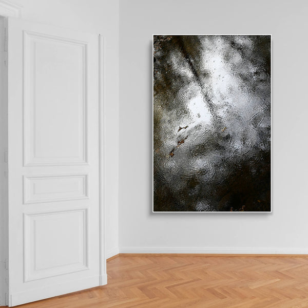 Wartezimmer mit Holzparkett und Schallschutzbild mit abstrakter Wasseroberfläche im Hochformat mit weißem Bilderrahmen.