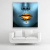 Schallschutzbild Golden Lips mit blauem, weiblichen Gesicht mit goldener, flüssigen Farbe auf den Lippen. Weißer Rahmen im Quadrat.