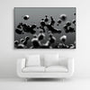 Tysta Akustikbild mit Makroaufnahme von schwebenden, schwarzen Tropfen. Schwarzer Bilderrahmen im Querformat 3 zu 2 über weißem Sofa.