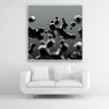 Tysta Akustikbild mit Makroaufnahme von schwebenden, schwarzen Tropfen. Weißer Bilderrahmen im Quadrat über weißem Sofa.