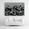 Tysta Akustikbild mit Makroaufnahme von schwebenden, schwarzen Tropfen. Weißer Bilderrahmen im Querformat 3 zu 2 über weißem Sofa.