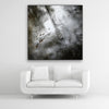 Schallschutzbild mit abstrakter Wasseroberfläche quadratisch mit schwarzem Bilderrahmen über weißem Sofa.